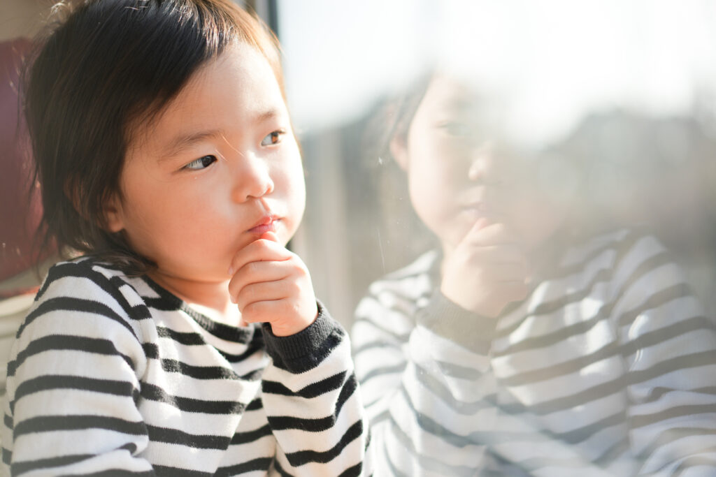 顎に手を当てて窓の外を見て悩む女の子