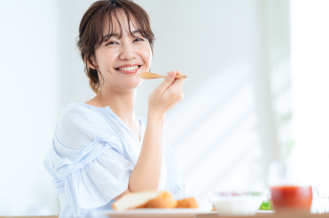 親知らずを抜歯し笑顔で食事をする女性